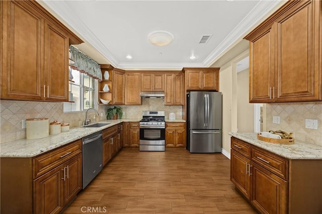 kitchen with open shelves, under cabinet range hood, brown cabinets, a sink, and appliances with stainless steel finishes