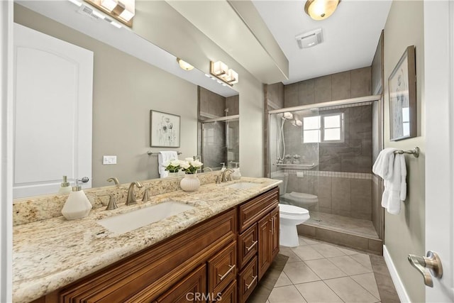 full bathroom with double vanity, tile patterned flooring, a stall shower, a sink, and toilet