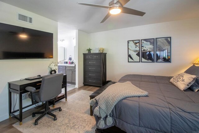 bedroom featuring a ceiling fan, connected bathroom, wood finished floors, and visible vents