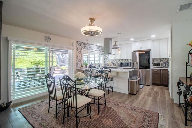 dining area featuring visible vents, light wood-style flooring, and a toaster
