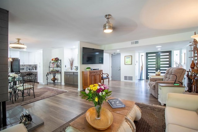 living room featuring a ceiling fan, visible vents, and wood finished floors