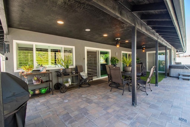 view of patio featuring a ceiling fan, a hot tub, and outdoor dining space