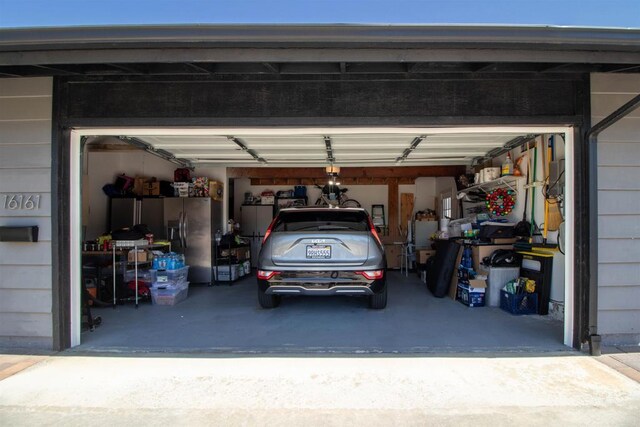 garage featuring stainless steel fridge and concrete driveway