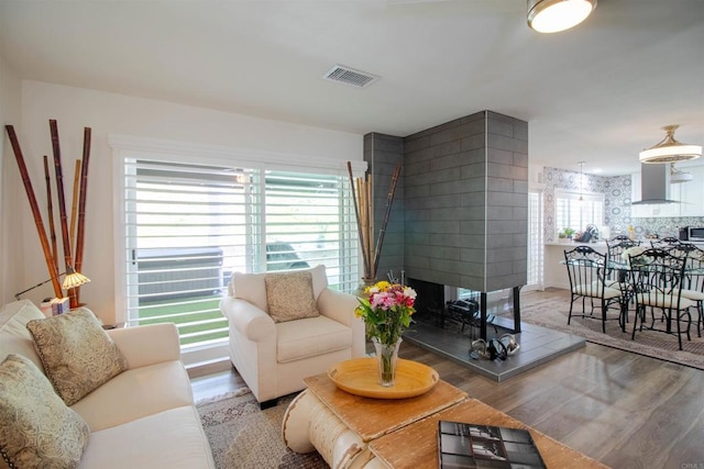 living area with a multi sided fireplace, wood finished floors, and visible vents