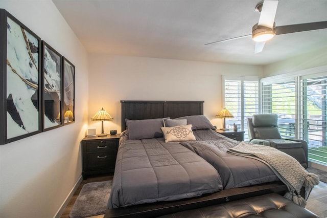 bedroom featuring baseboards, a ceiling fan, wood finished floors, and multiple windows