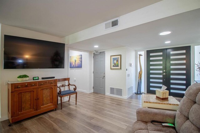 living room featuring light wood-style floors, baseboards, recessed lighting, and visible vents