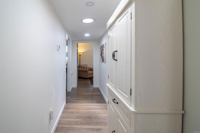 corridor with baseboards and light wood-type flooring