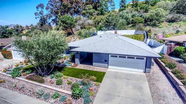 ranch-style house featuring an attached garage, a shingled roof, fence, and concrete driveway