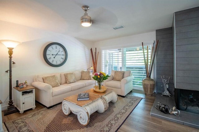 living room featuring light wood-style floors, a ceiling fan, and visible vents