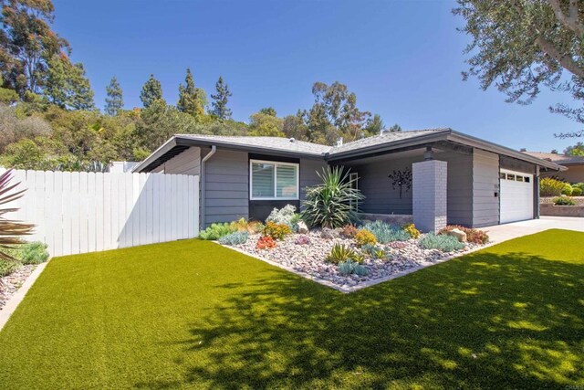 view of front facade with an attached garage, a front lawn, fence, and concrete driveway