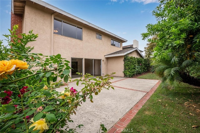 rear view of house with a patio and stucco siding