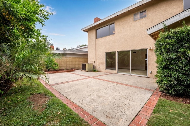 back of house with fence, stucco siding, a chimney, a patio area, and central air condition unit