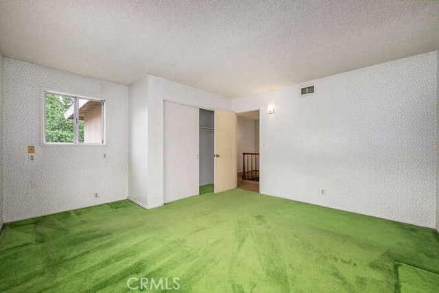 interior space with a textured ceiling, visible vents, and carpet