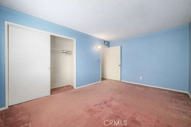 unfurnished bedroom featuring carpet floors, a textured ceiling, baseboards, and a closet