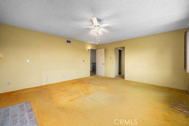 empty room featuring visible vents, a textured ceiling, ceiling fan, and light carpet