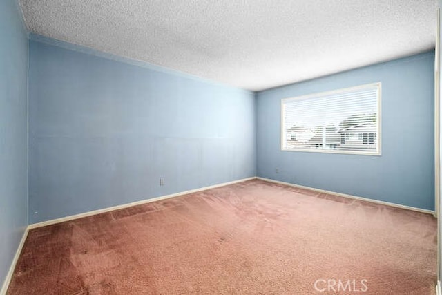 carpeted empty room with a textured ceiling and baseboards