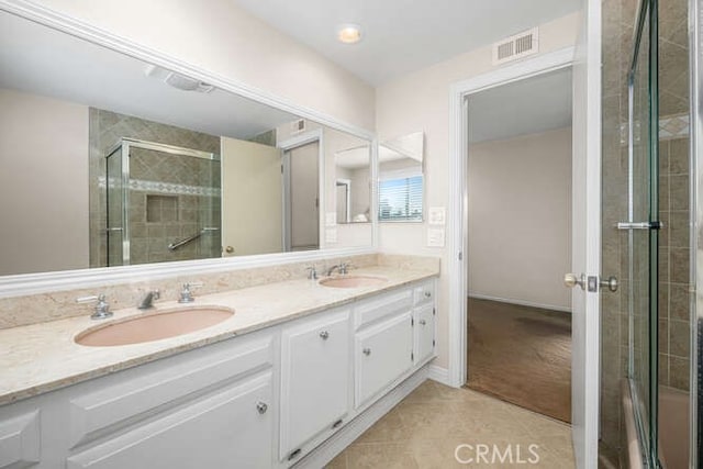 bathroom featuring a sink, a shower stall, double vanity, and visible vents