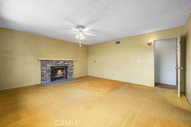 unfurnished living room featuring carpet floors, a brick fireplace, a textured ceiling, a ceiling fan, and visible vents
