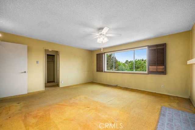 interior space with carpet floors, ceiling fan, and a textured ceiling