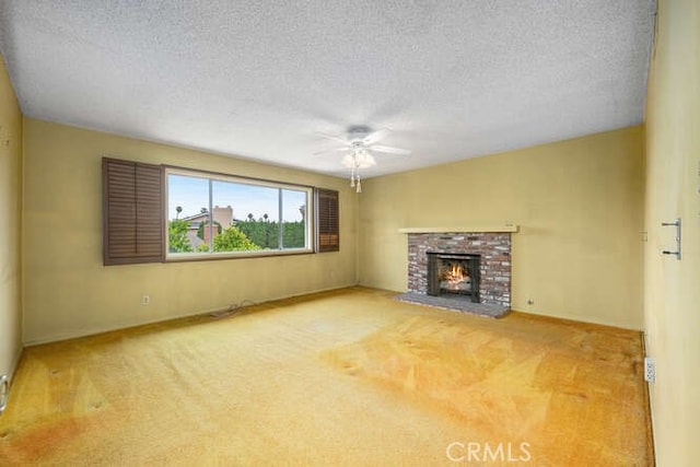 unfurnished living room featuring a ceiling fan, a textured ceiling, carpet flooring, and a fireplace