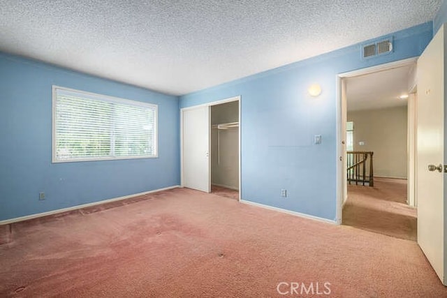 unfurnished bedroom featuring a textured ceiling, visible vents, carpet, and a closet