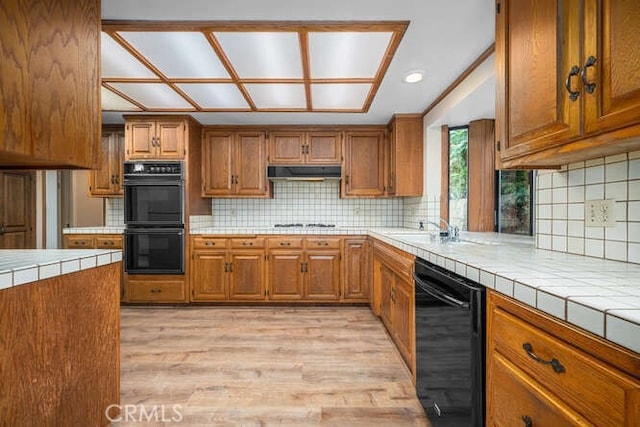 kitchen with tile counters, brown cabinetry, and black appliances