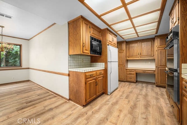 kitchen featuring visible vents, brown cabinetry, freestanding refrigerator, black microwave, and double wall oven