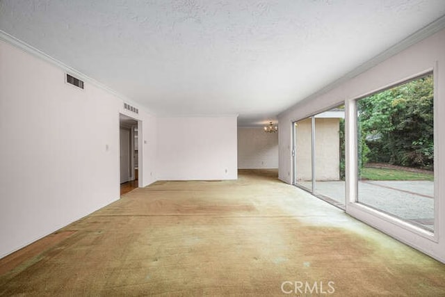empty room featuring ornamental molding, a chandelier, and visible vents