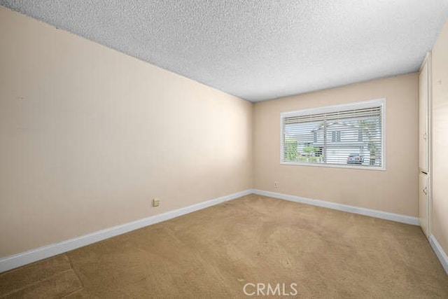 carpeted empty room featuring baseboards and a textured ceiling