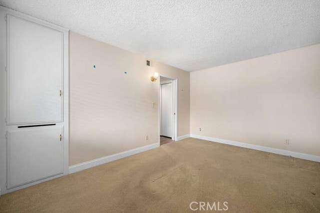 spare room with carpet floors, baseboards, and a textured ceiling