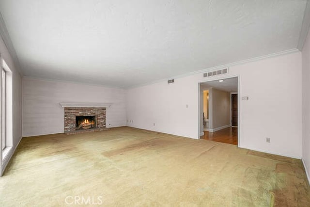 unfurnished living room featuring visible vents, crown molding, carpet floors, and a fireplace