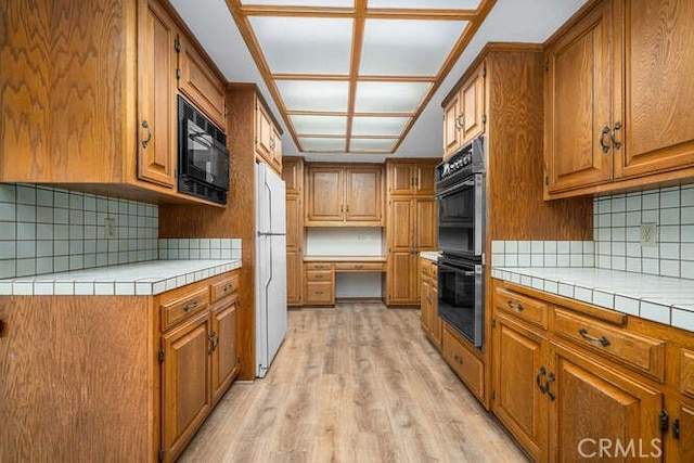 kitchen with tile counters, brown cabinets, and black appliances