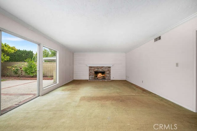 unfurnished living room with carpet flooring, a warm lit fireplace, and visible vents
