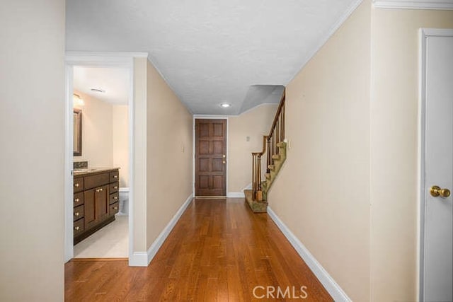 hall with light wood-style floors, baseboards, and stairway