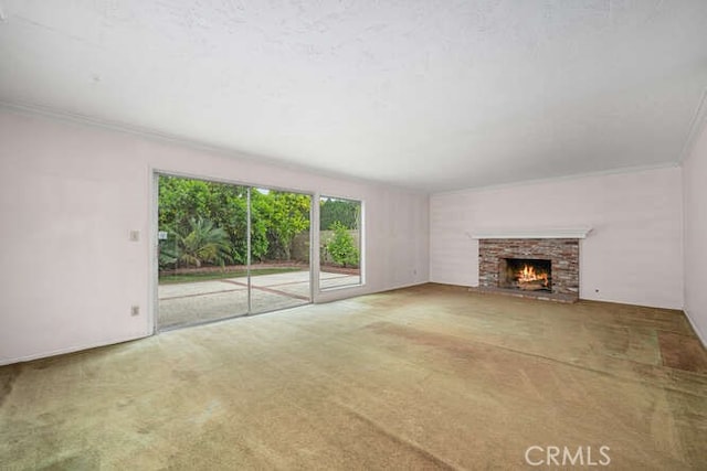 unfurnished living room featuring carpet flooring, a warm lit fireplace, and ornamental molding