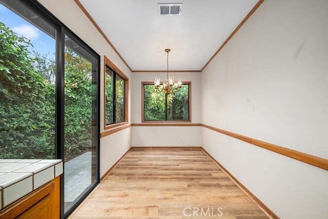 interior space with visible vents, a healthy amount of sunlight, a chandelier, and light wood-type flooring