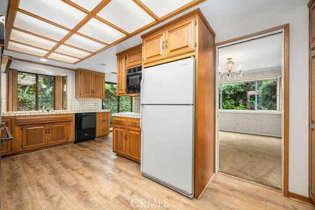 kitchen with plenty of natural light, freestanding refrigerator, black dishwasher, and tile countertops
