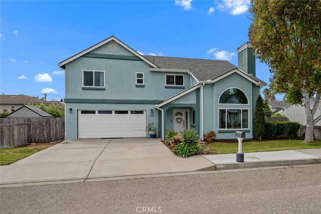 traditional-style home featuring a garage, fence, stucco siding, a chimney, and driveway