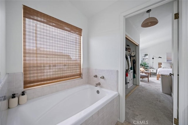 ensuite bathroom featuring vaulted ceiling, ensuite bathroom, and a bath