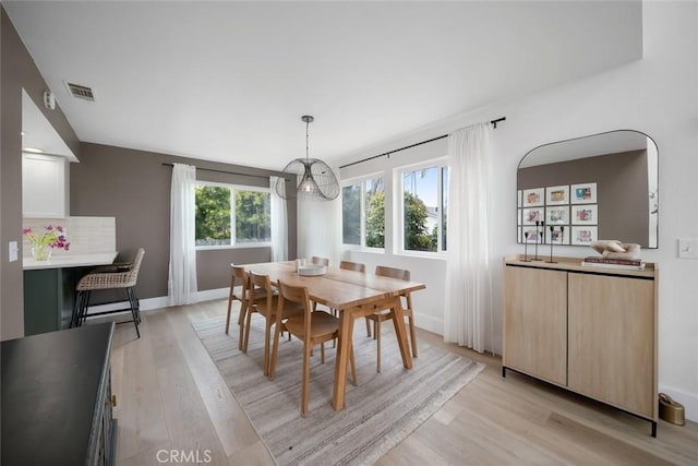 dining area featuring baseboards, visible vents, light wood-style flooring, and an inviting chandelier