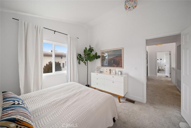 bedroom featuring visible vents, baseboards, light colored carpet, and vaulted ceiling