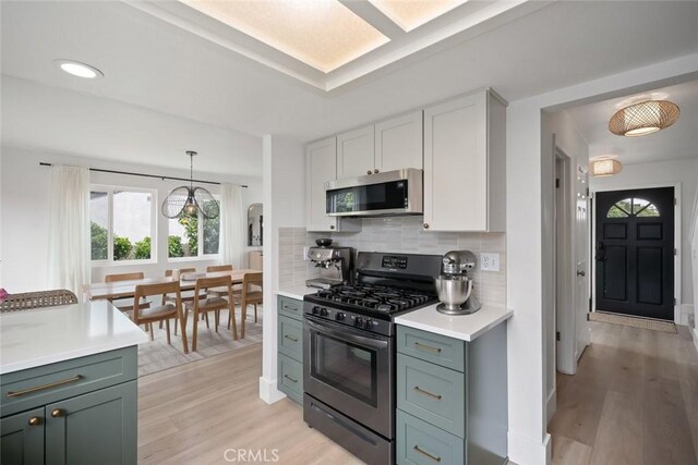kitchen featuring light countertops, light wood-style flooring, a healthy amount of sunlight, and stainless steel appliances