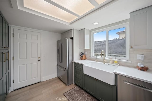 kitchen featuring high end fridge, a sink, light wood-style flooring, and decorative backsplash
