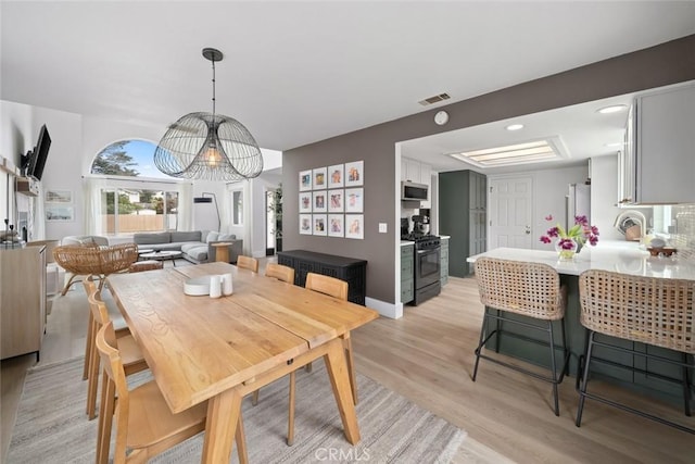 dining area with a notable chandelier, visible vents, and light wood-type flooring