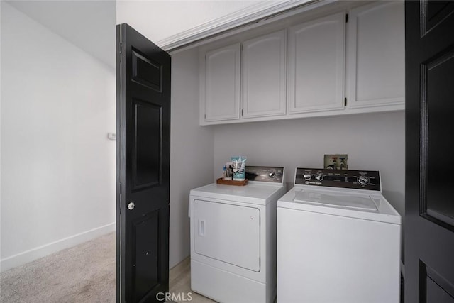 washroom with cabinet space, baseboards, light colored carpet, and washing machine and dryer