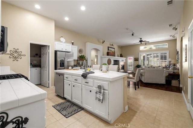 kitchen with visible vents, tile counters, arched walkways, a ceiling fan, and appliances with stainless steel finishes