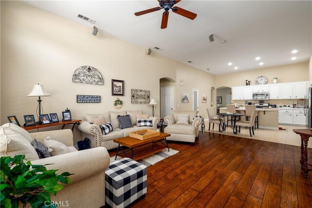 living room featuring wood-type flooring, arched walkways, a ceiling fan, recessed lighting, and visible vents
