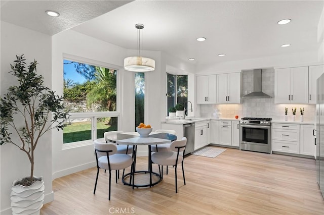 101 Fairlane Rd, Laguna Niguel, CA 92677 - kitchen featuring appliances with stainless steel finishes, a sink, wall chimney exhaust hood, decorative backsplash, and light wood-type flooring