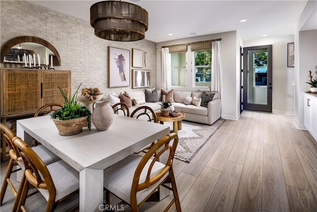 dining area featuring baseboards, recessed lighting, light wood finished floors, and brick wall