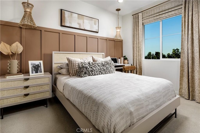 bedroom with wainscoting, carpet, and a decorative wall